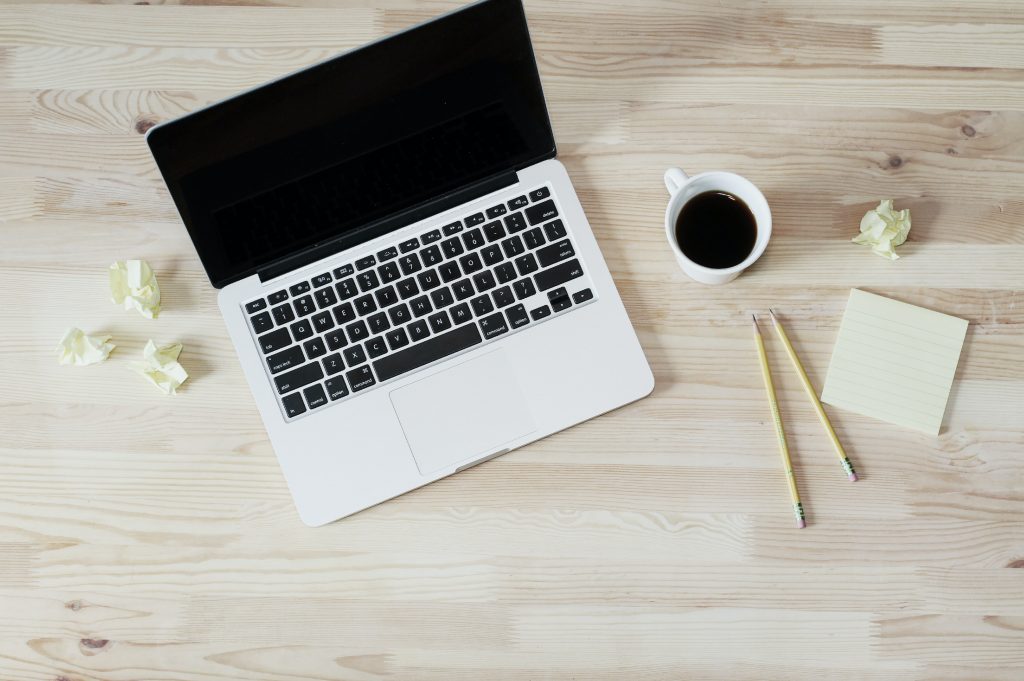 laptop on table with pens and coffee