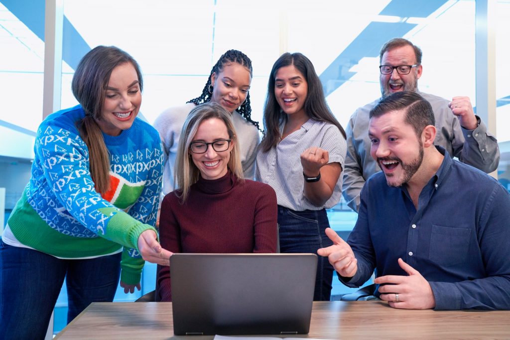 Coworkers celebrating around a laptop